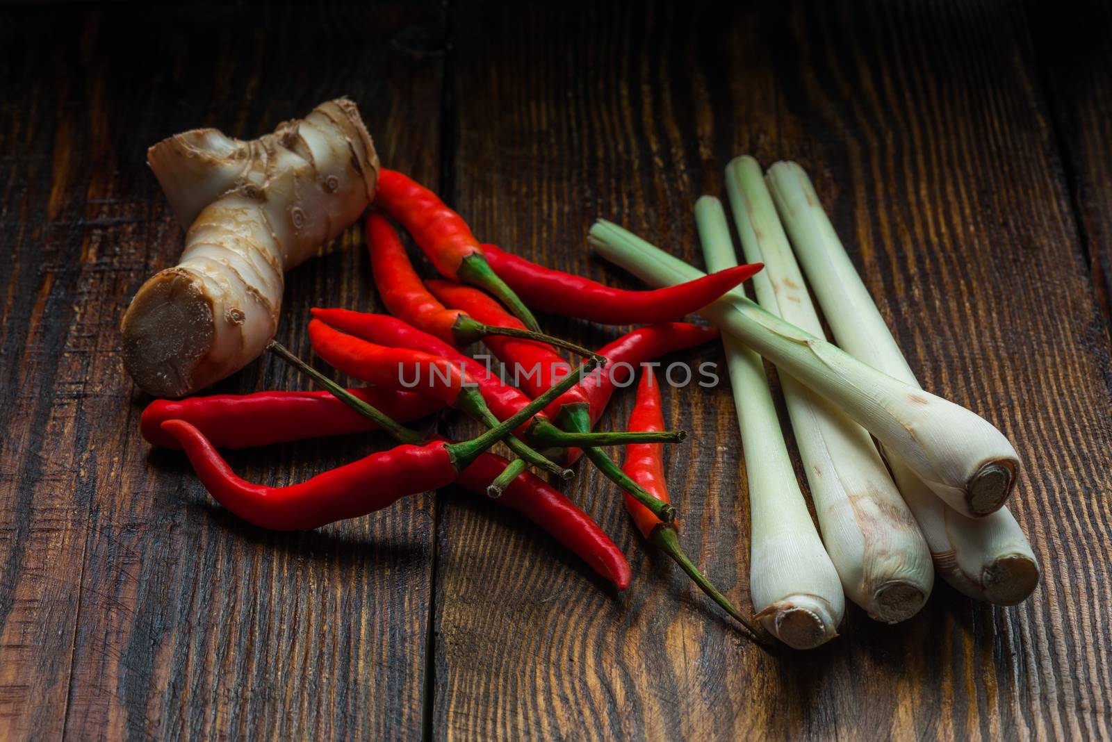 Galangal root, Mexican chili peppers with lemongrass on dark wooden table. Tom yam ingredients.
