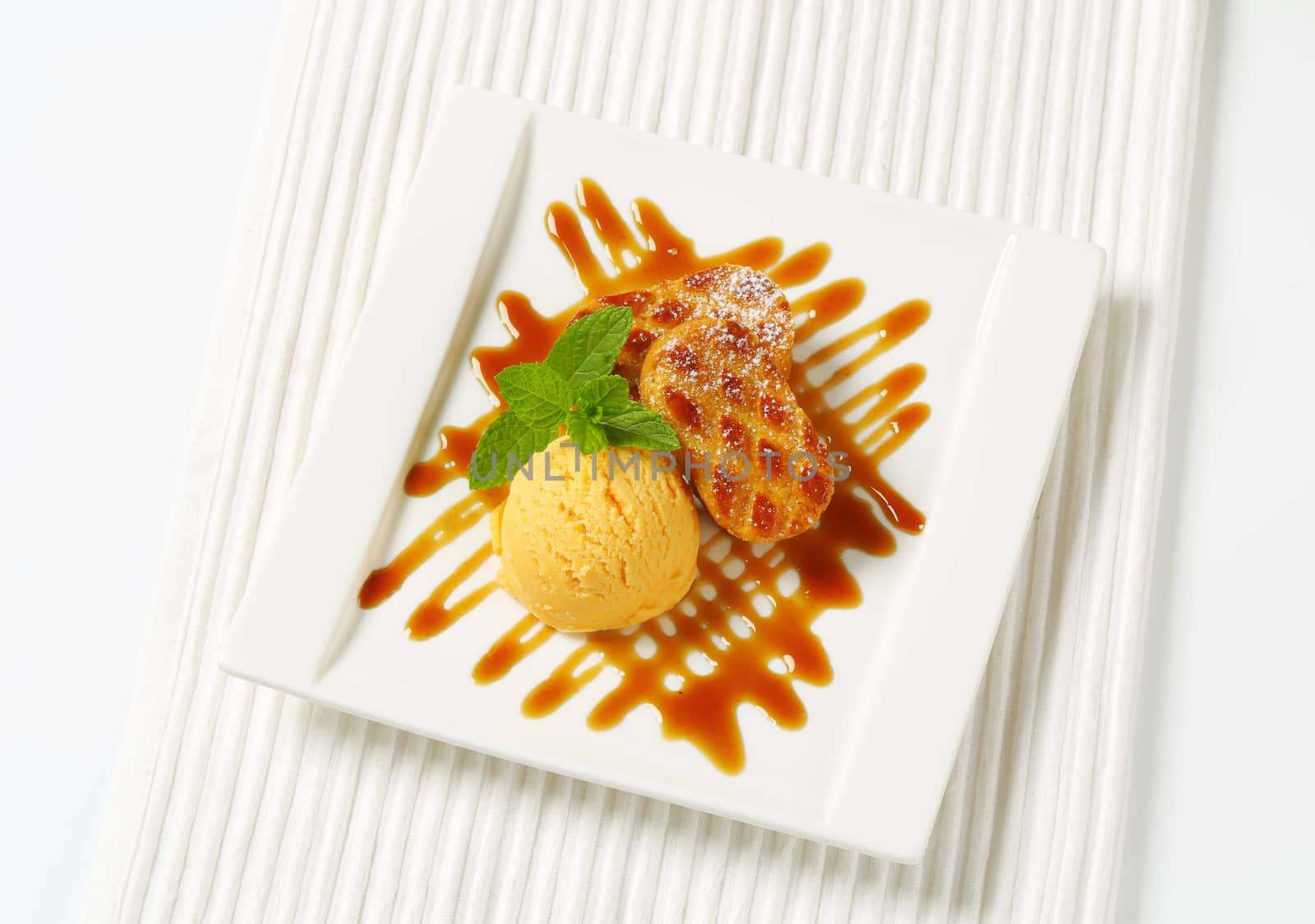 Small almond filled cookies served with caramel sauce and scoop of ice cream