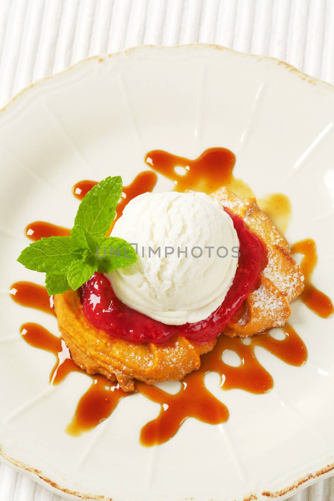 Spritz butter cookie with raspberry sauce and scoop of white ice cream
