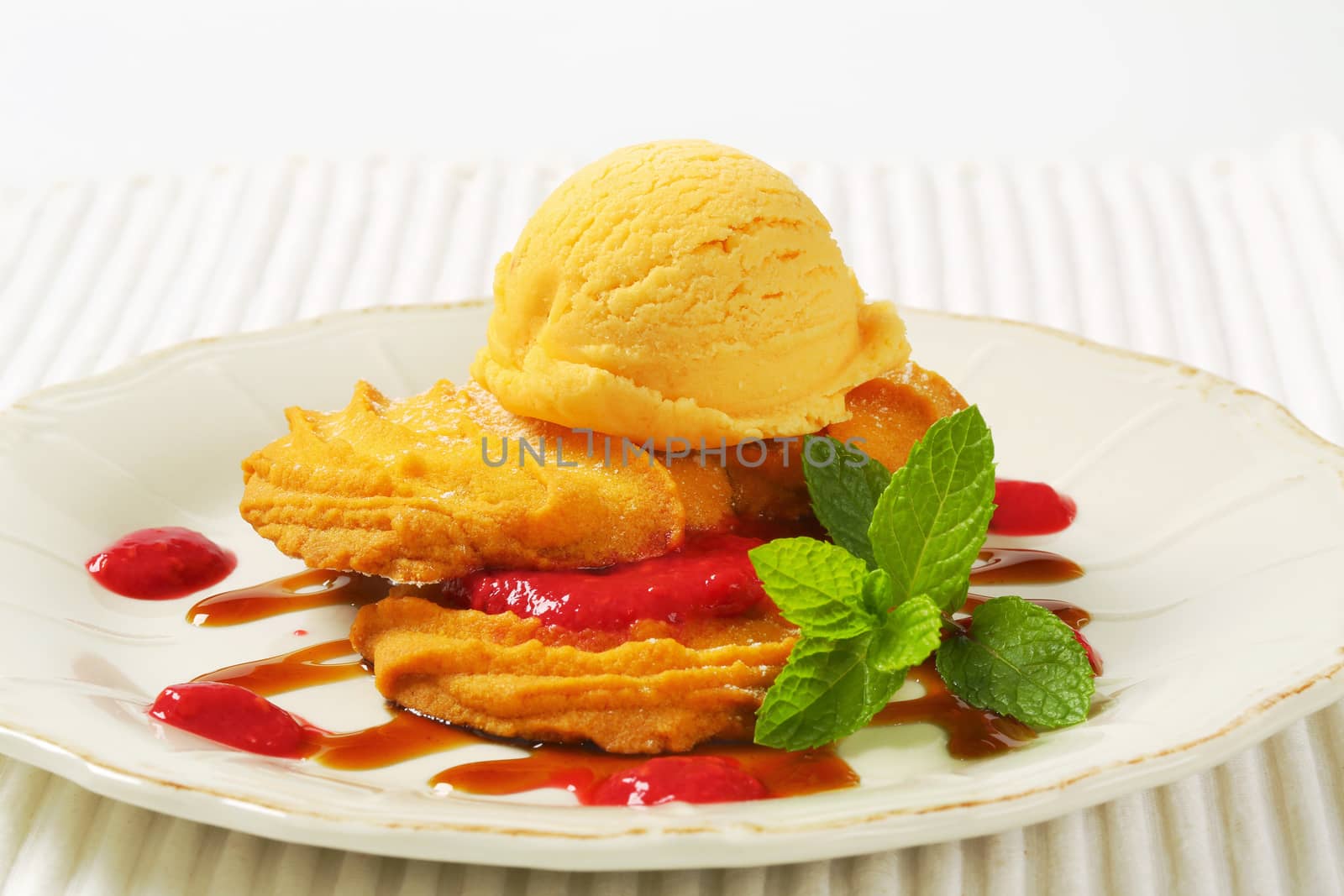 Spritz butter cookies with raspberry sauce and scoop of yellow ice cream