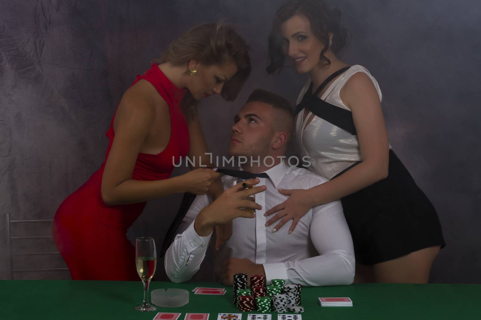 Two Women and a man at poker table with chips and drinks