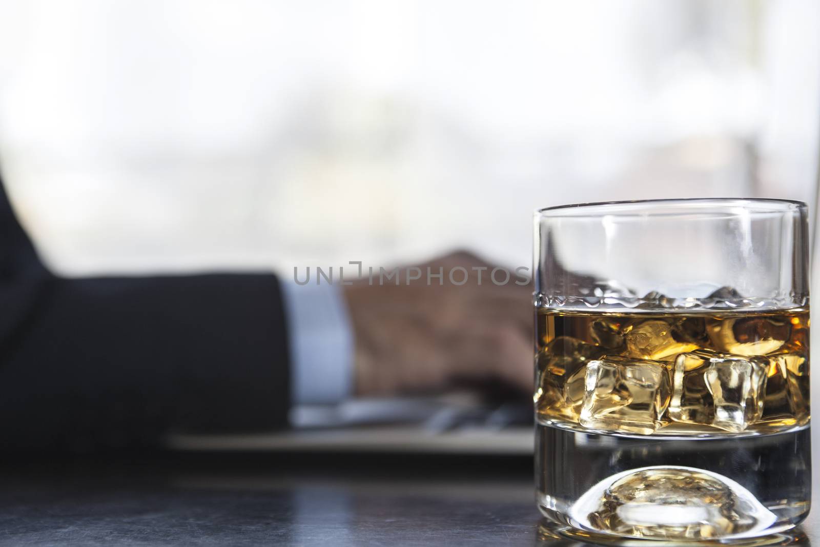 Man working on laptop with a glass of alcohol near him