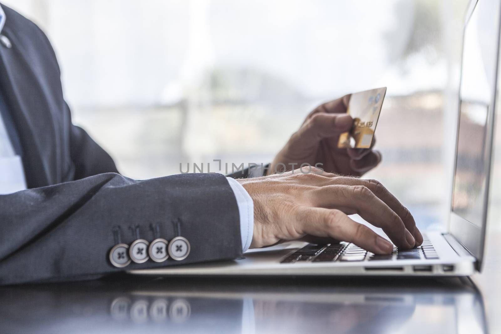 Man in suit using card and laptop