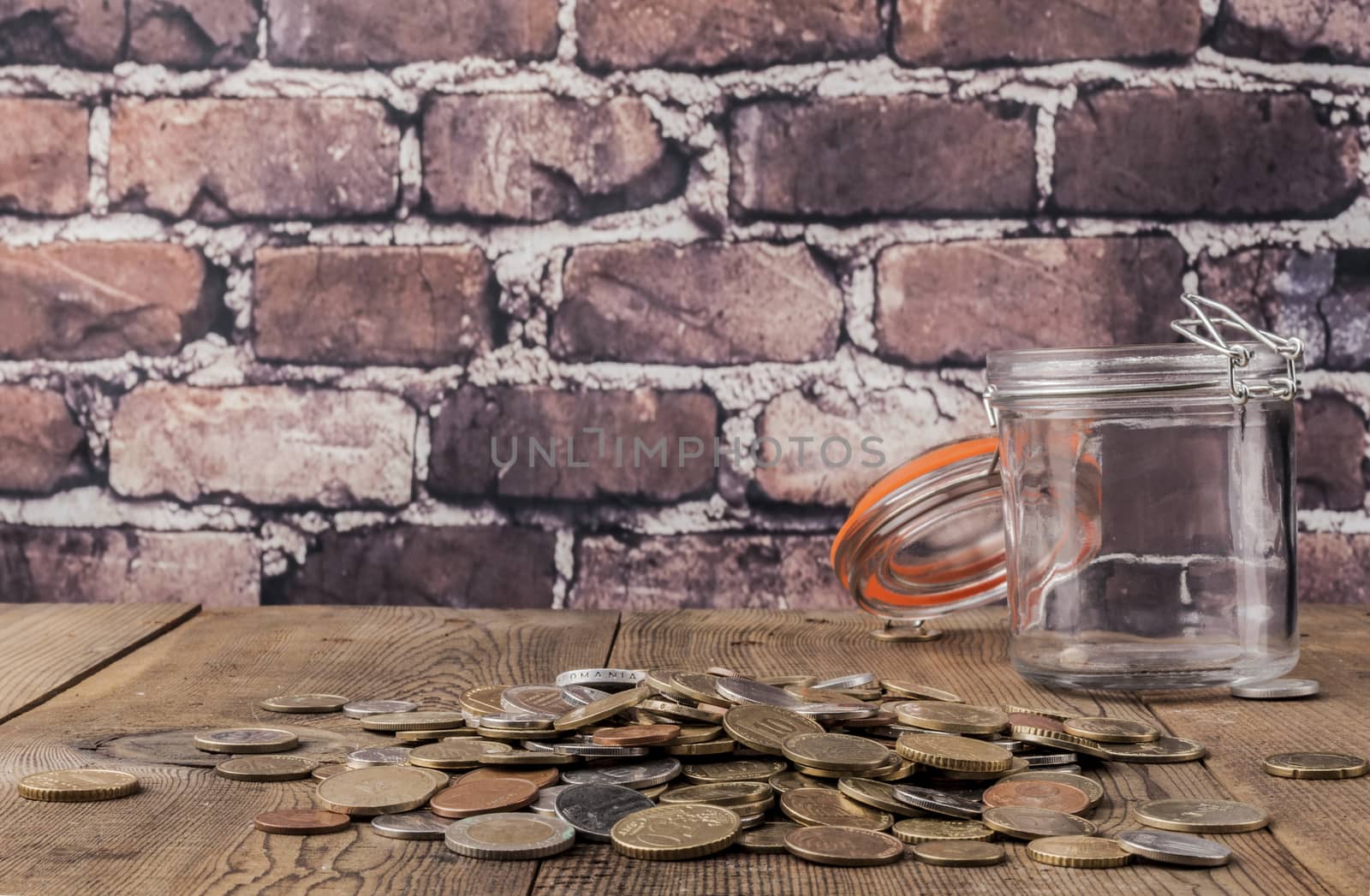 Jar and coins on wood table and brick background