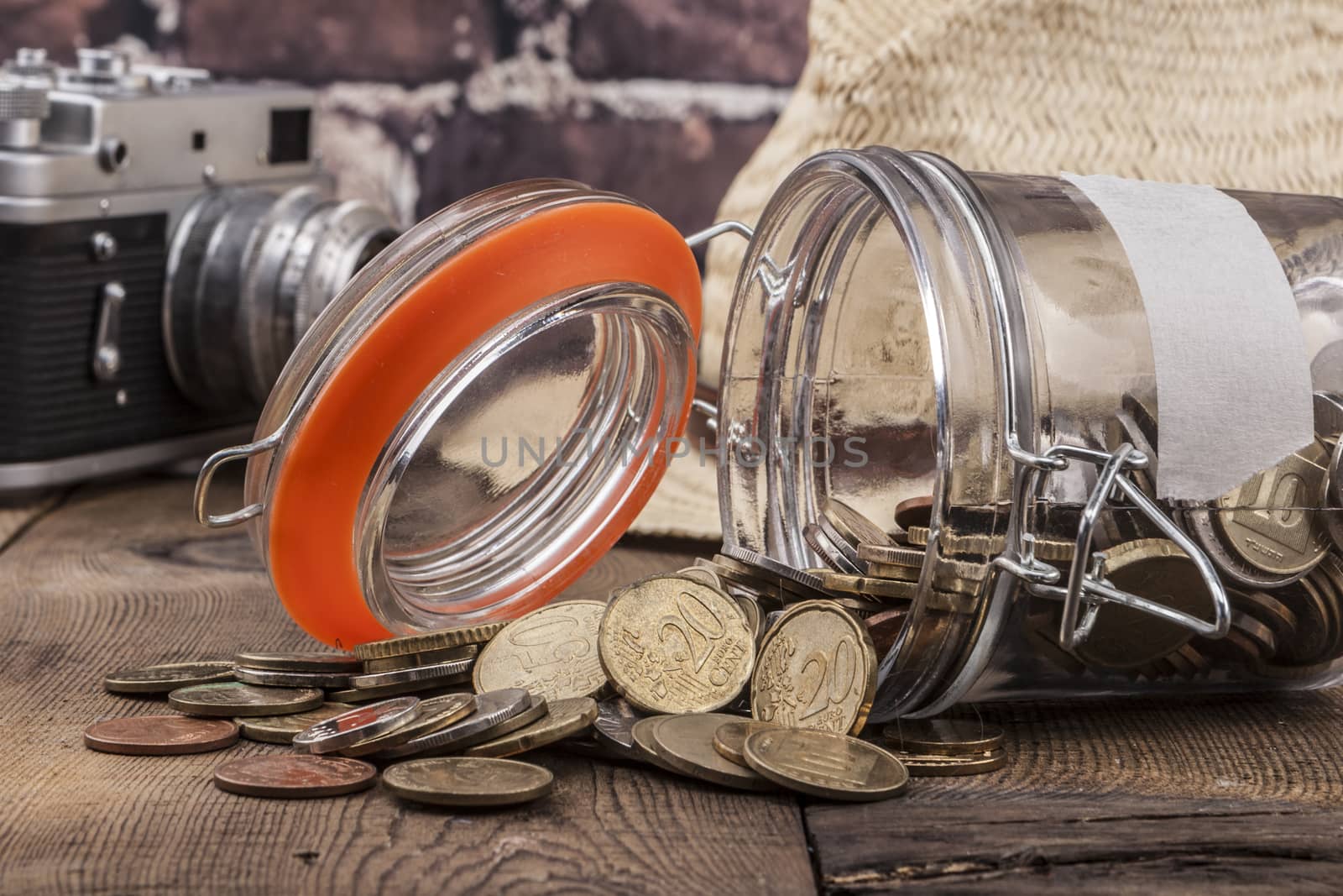 Jar and coins on wood table and brick background