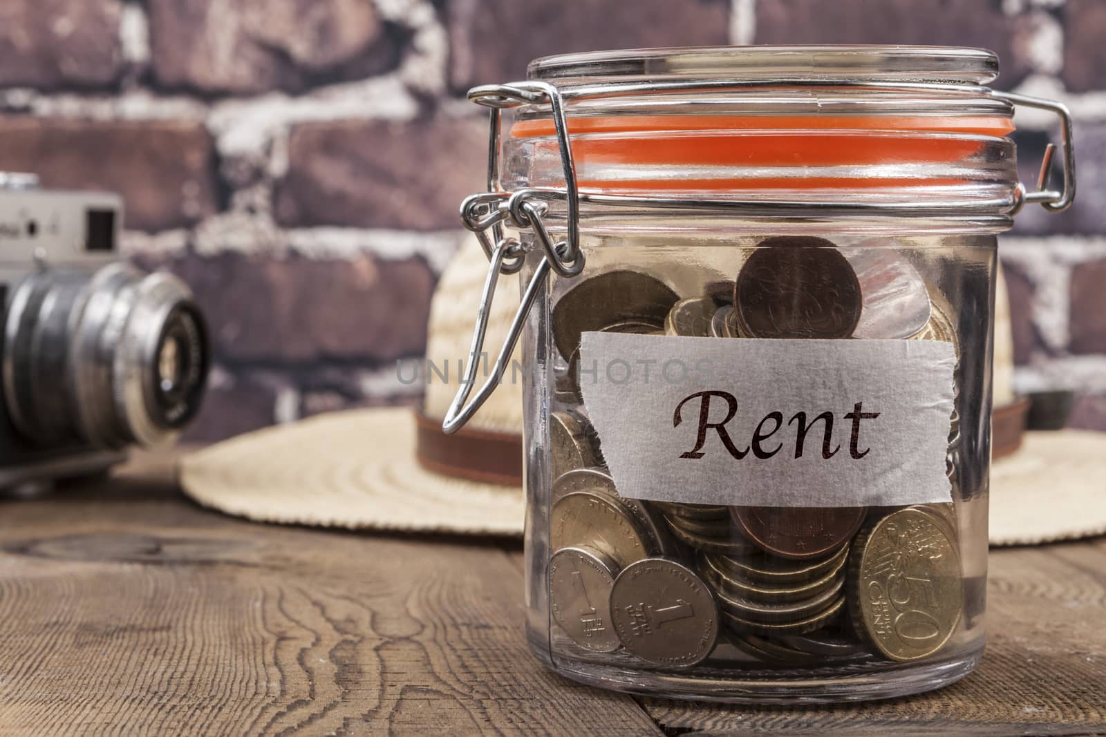 Coins in jar on wood table and brick background