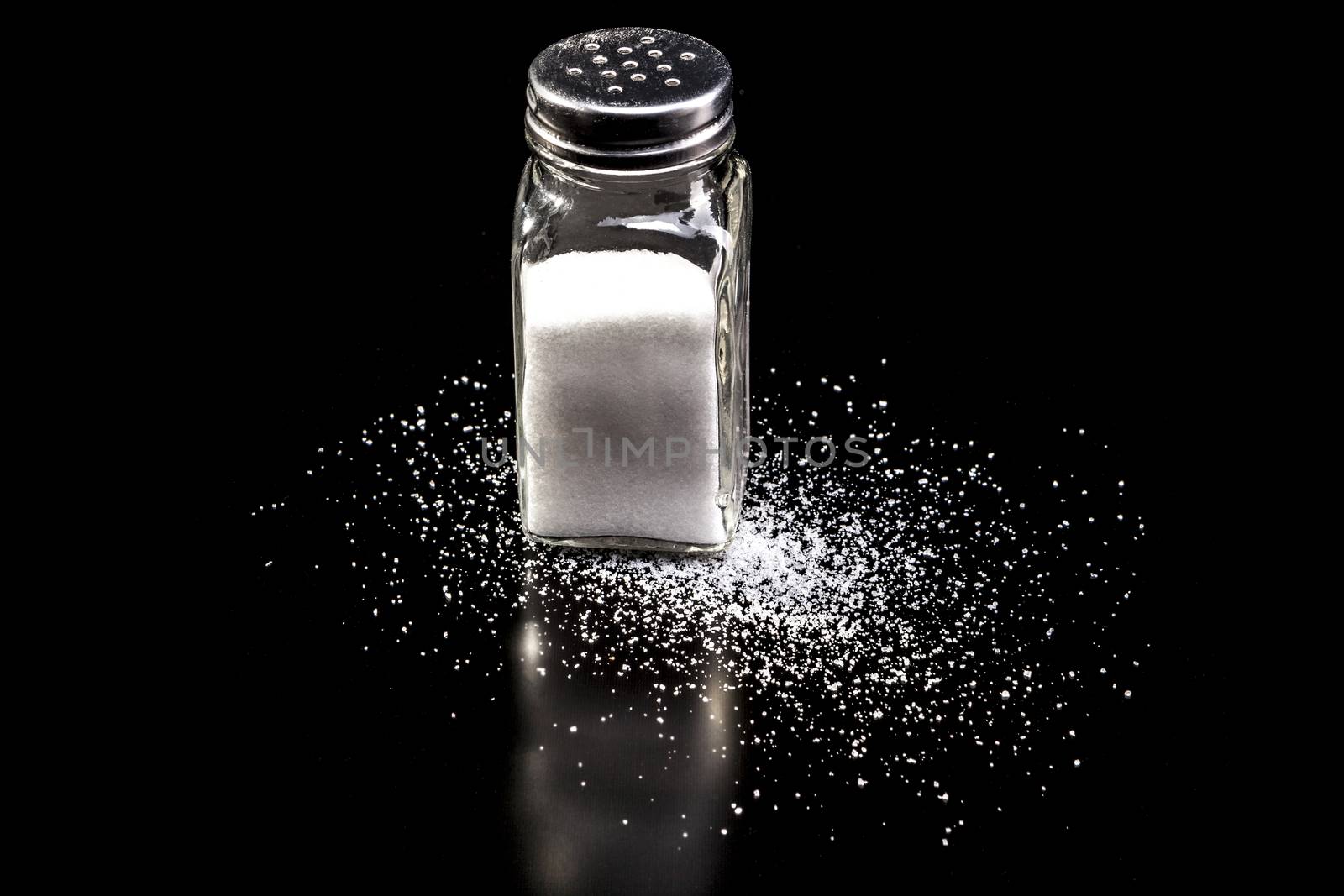 Jar with salt isolated on black background with reflection