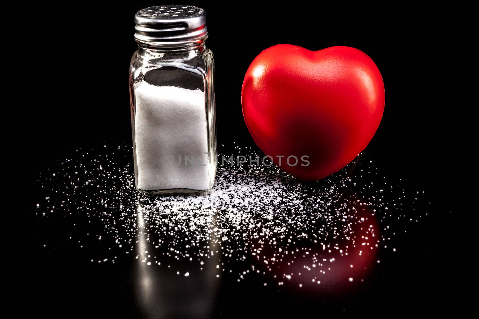 Salt and heart isolated on black background with reflection