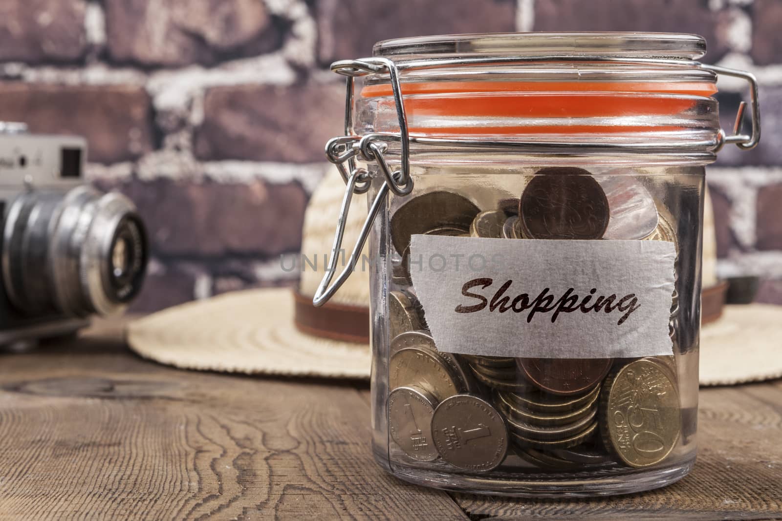 Coins in jar on wood table and brick background