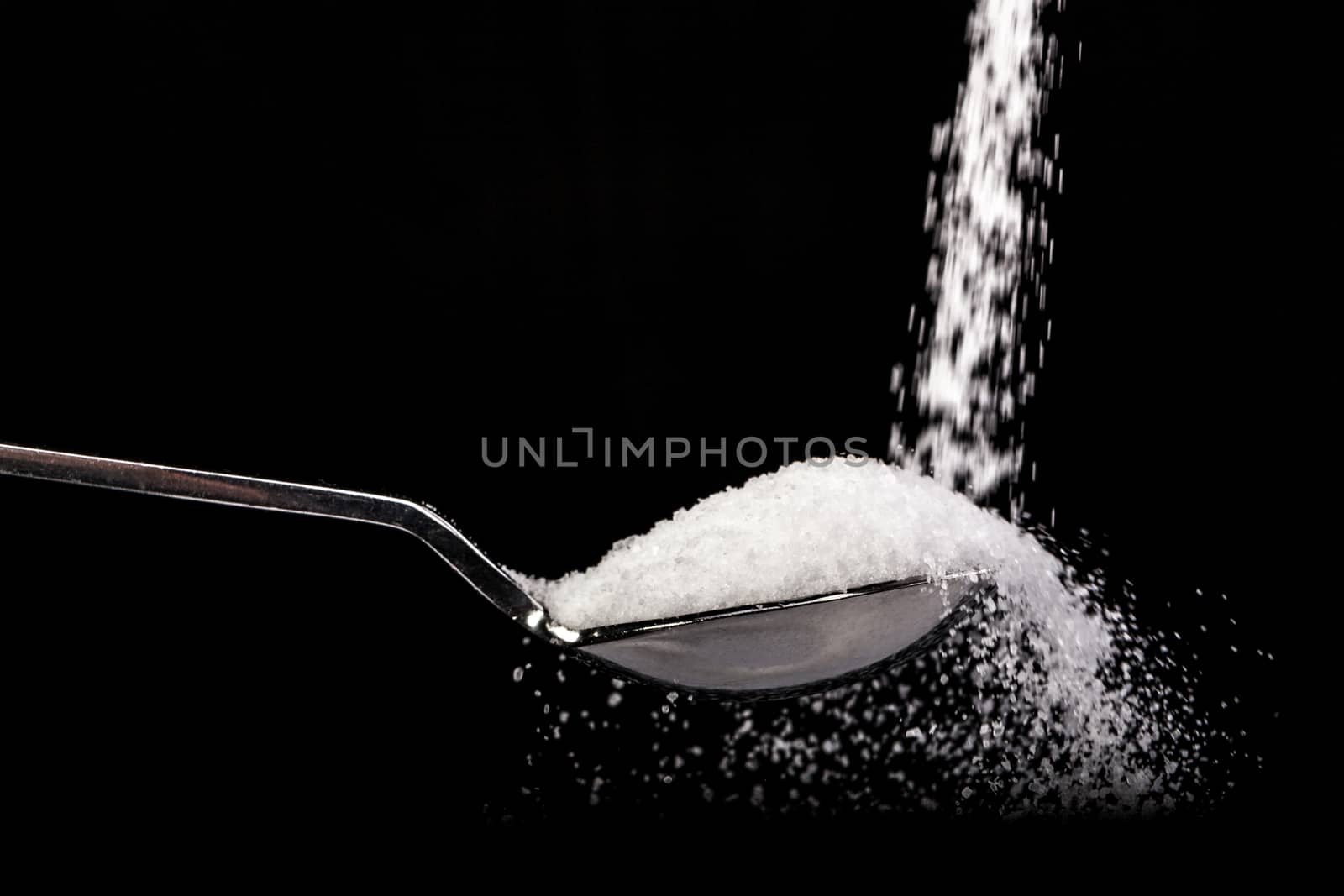 Salt and spoon isolated on black background