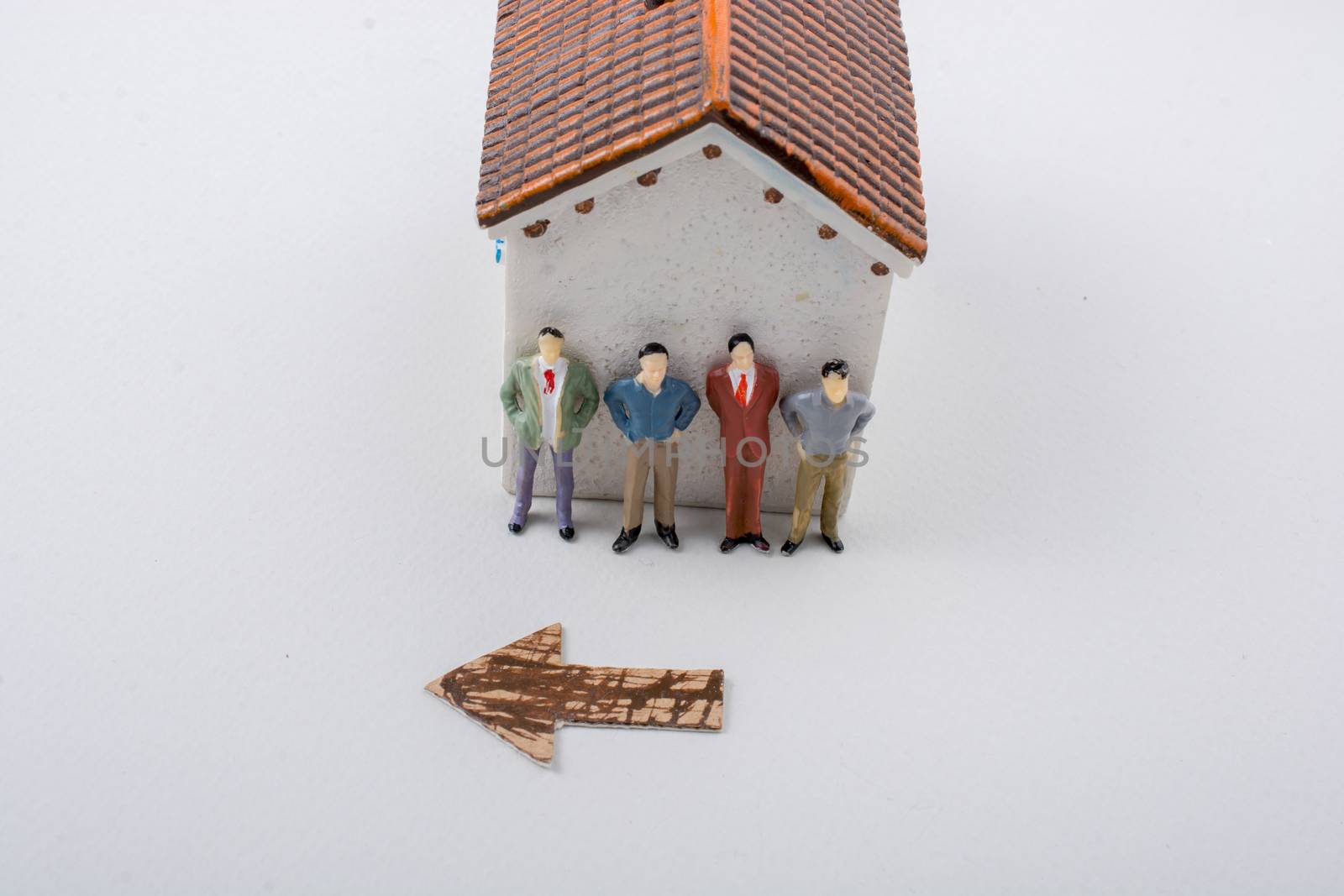 Tiny figurine of men and an arrow in front of a house by berkay