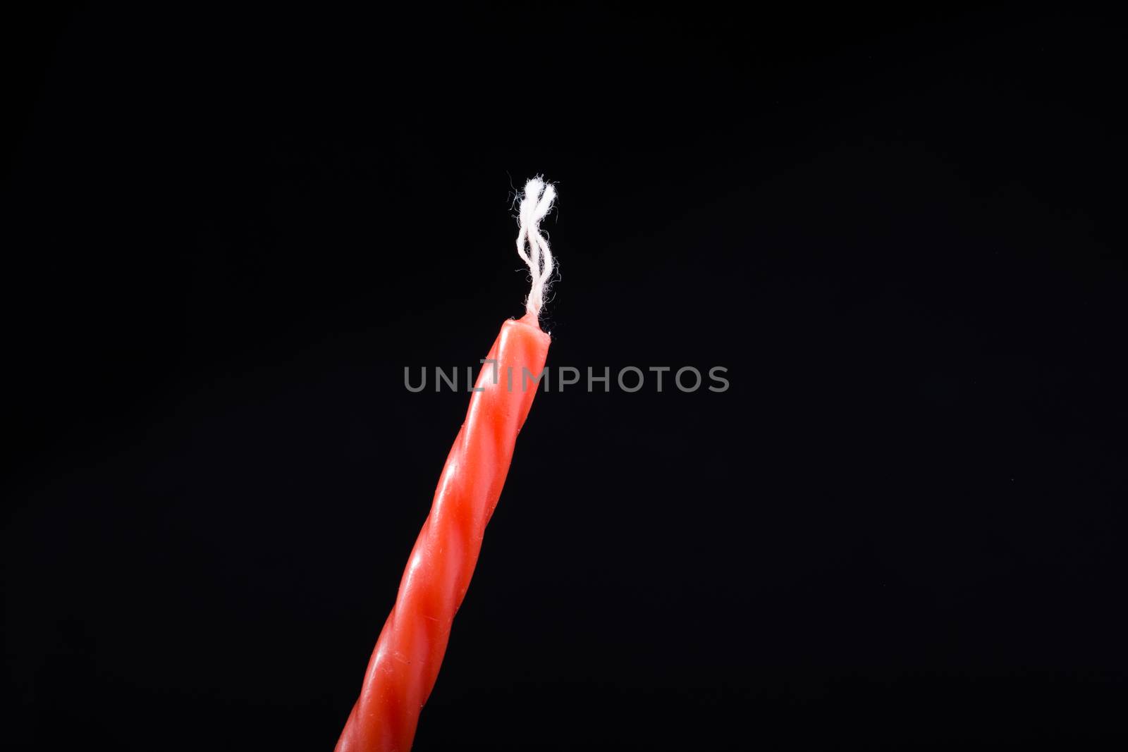 Colorful candle in hand on black background