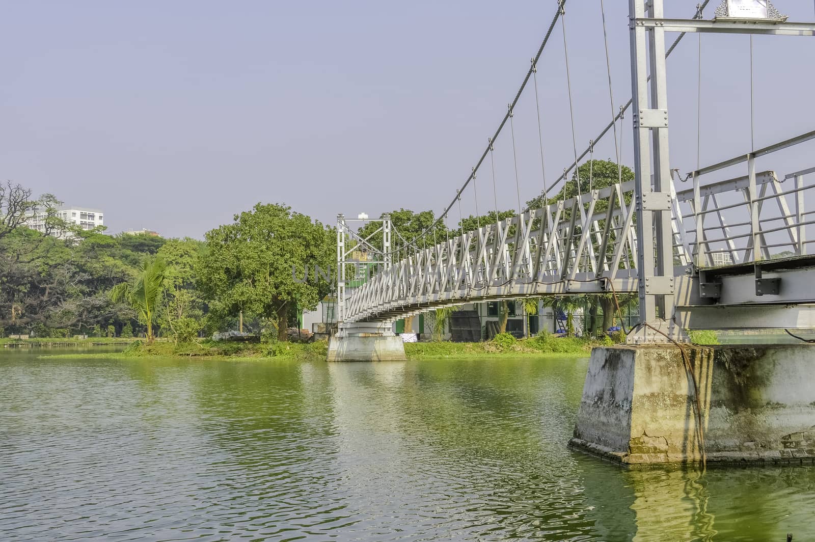 Small metal white footbridge over narrow canal in the park by sudiptabhowmick