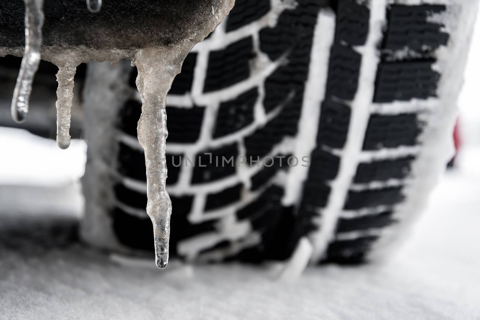 closeup of a tyre of a car with icicle in winter