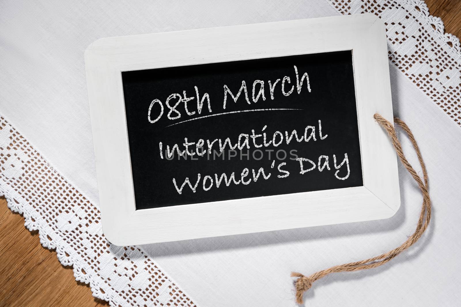 Image of a slate blackboard on a table with chalk message 8th March International Women's Day
