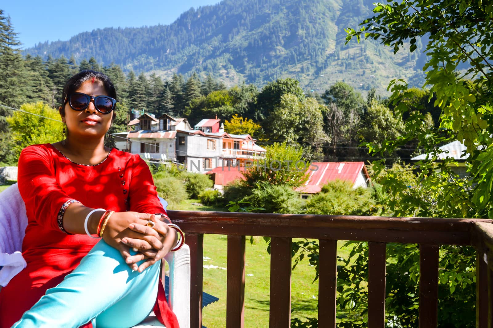 A lady resting or relaxing in balcony of a luxury resort bungalow in morning in the heart of Manali City, Himachal Pradesh, Kullu, India. It is a popular tourist destination in northern India.