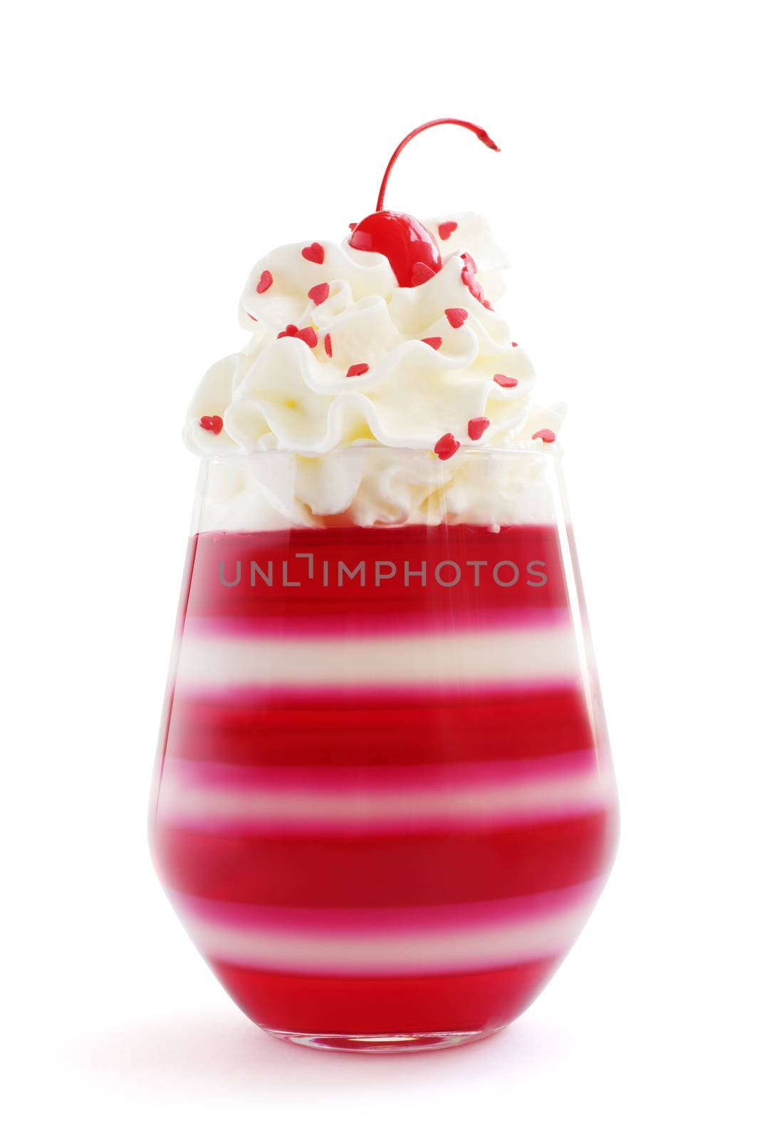 Red striped jello dessert in glass with whipped cream, red candied cherry and heart shape confectionery on top isolated on white background, Valentines day