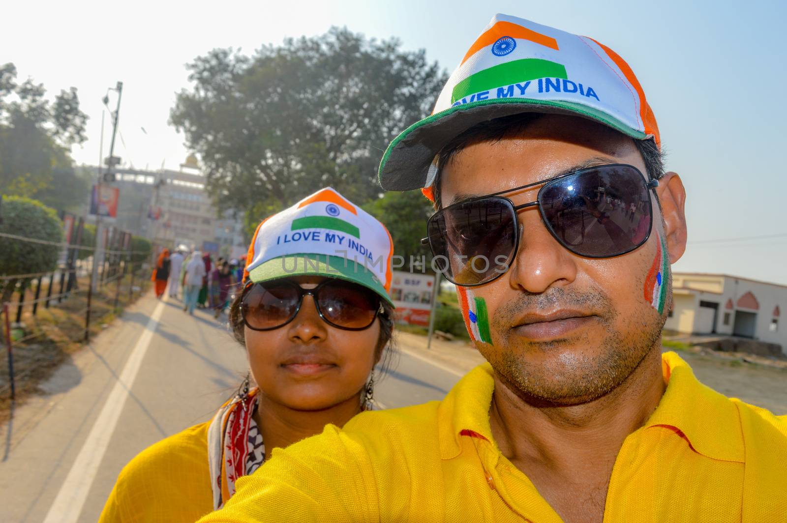 Selective focus on man. Cricket fans with painted face in Indian tricolor. Happy young loving couple looking at camera. Capturing bright cheerful moments taking Selfie on camera and standing outdoors.