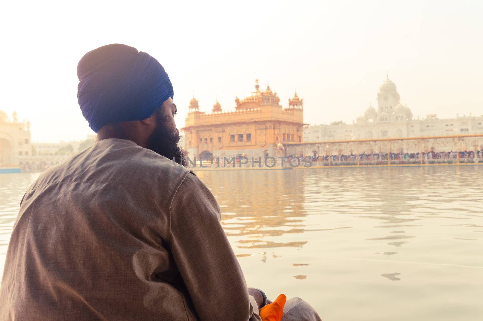 Unidentifiable Punjabi Sikh pilgrim devotee "Nihang Warrior" sitting by the holy pool and meditating in front of Golden Temple ("Harmandir Sahib Darbar Gurudwara") Amritsar, Punjab, India, Asia.