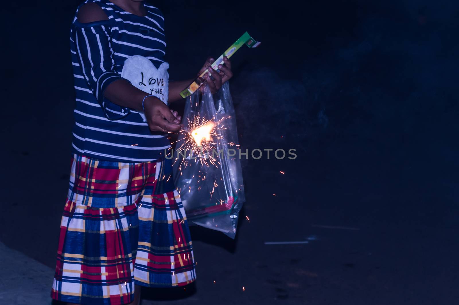 Sparklers on hand on black background on a low light evening. Selective focus on sparklers. Lady, girl, kid holding sparkles.