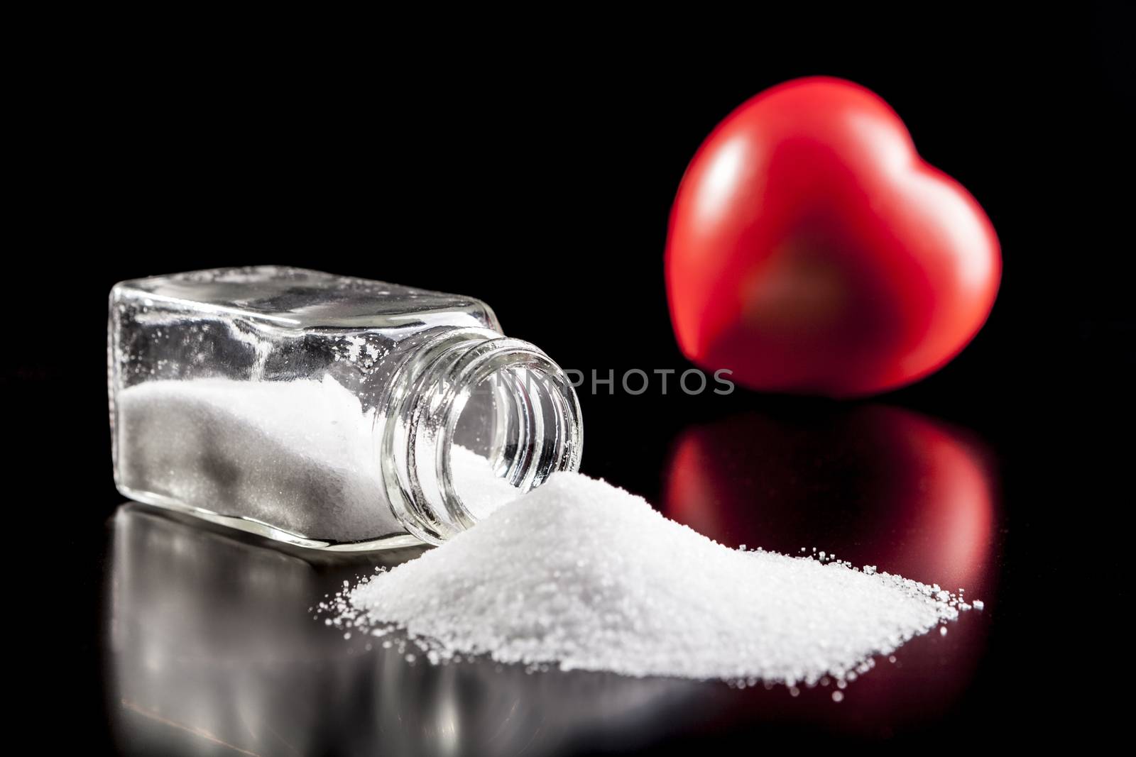 Heart and salt isolated on black background with reflection