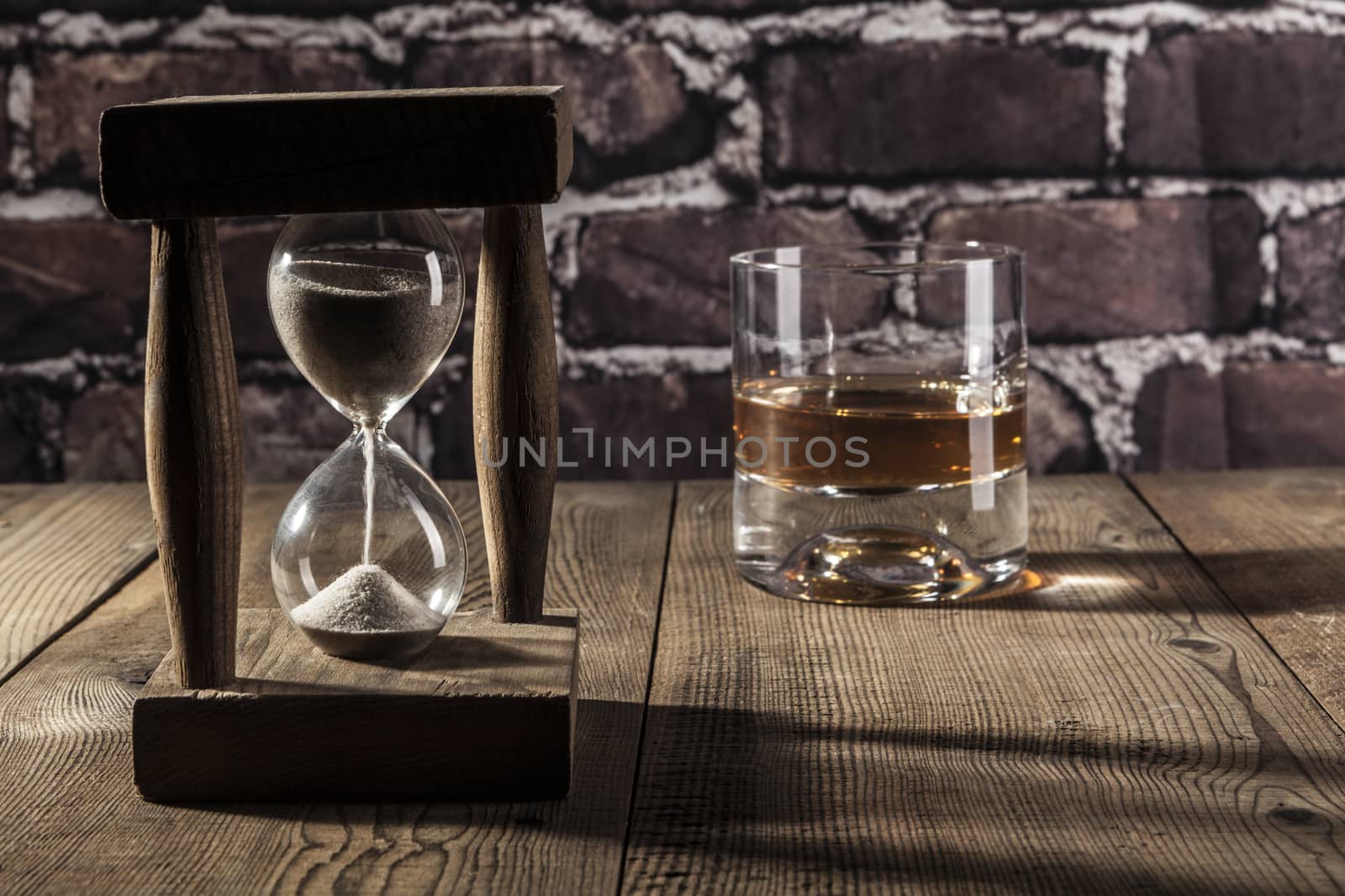 Hourglass and alcohol on brown wood table