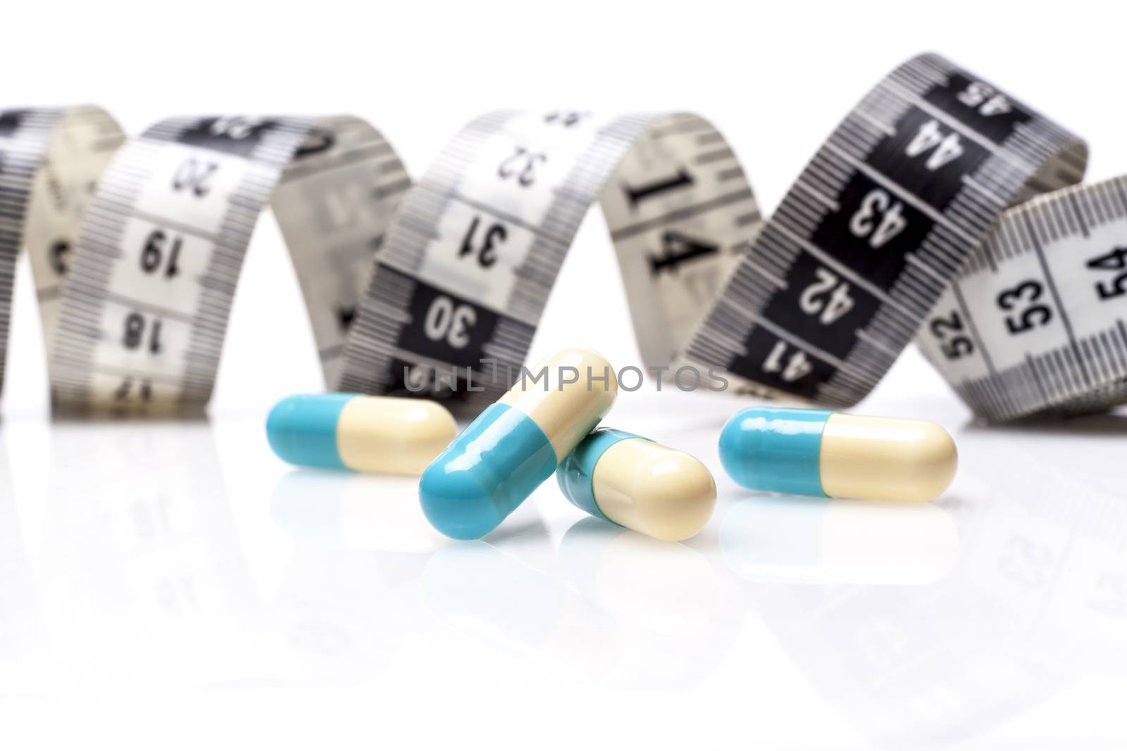 Blue Pills for Diet With Measuring Tape on White Background
