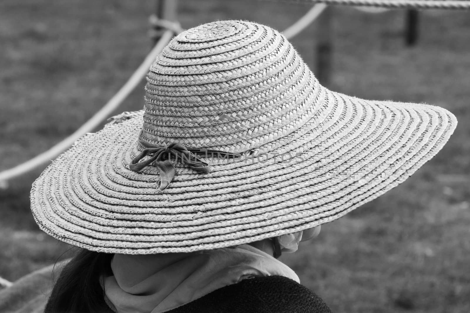 Woman wearing a traditional straw hat, her face hidden at a Medieval festival - monochrome processing