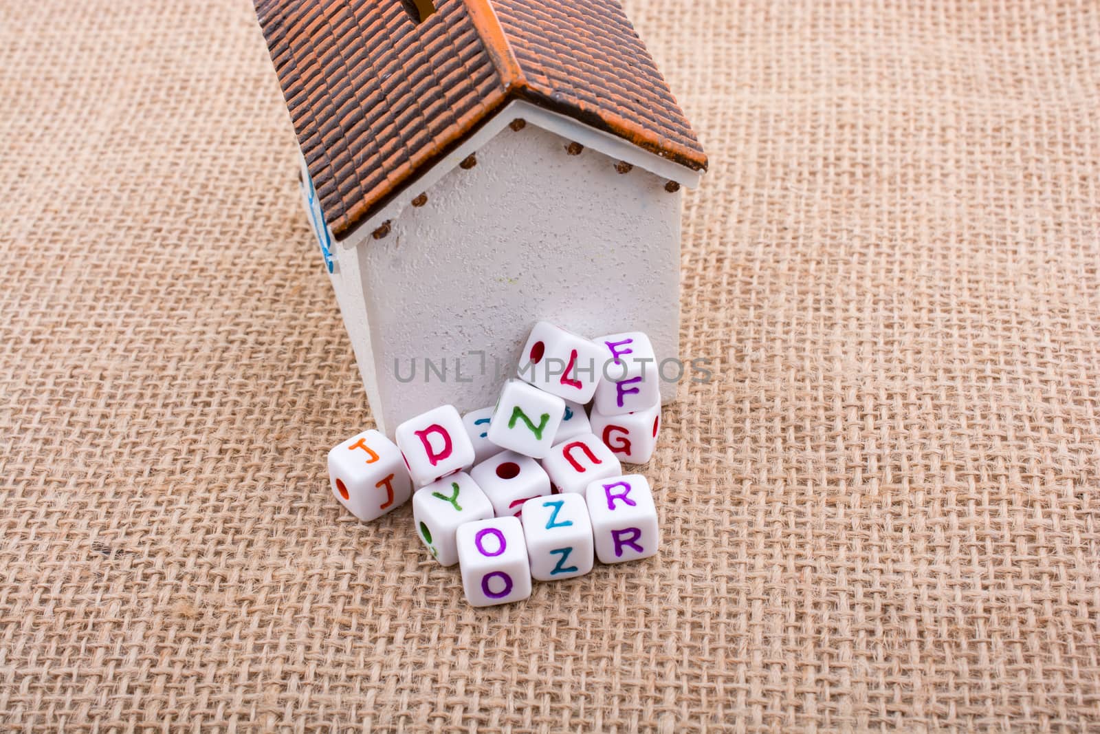 Leter cubes and little model house on a canvas