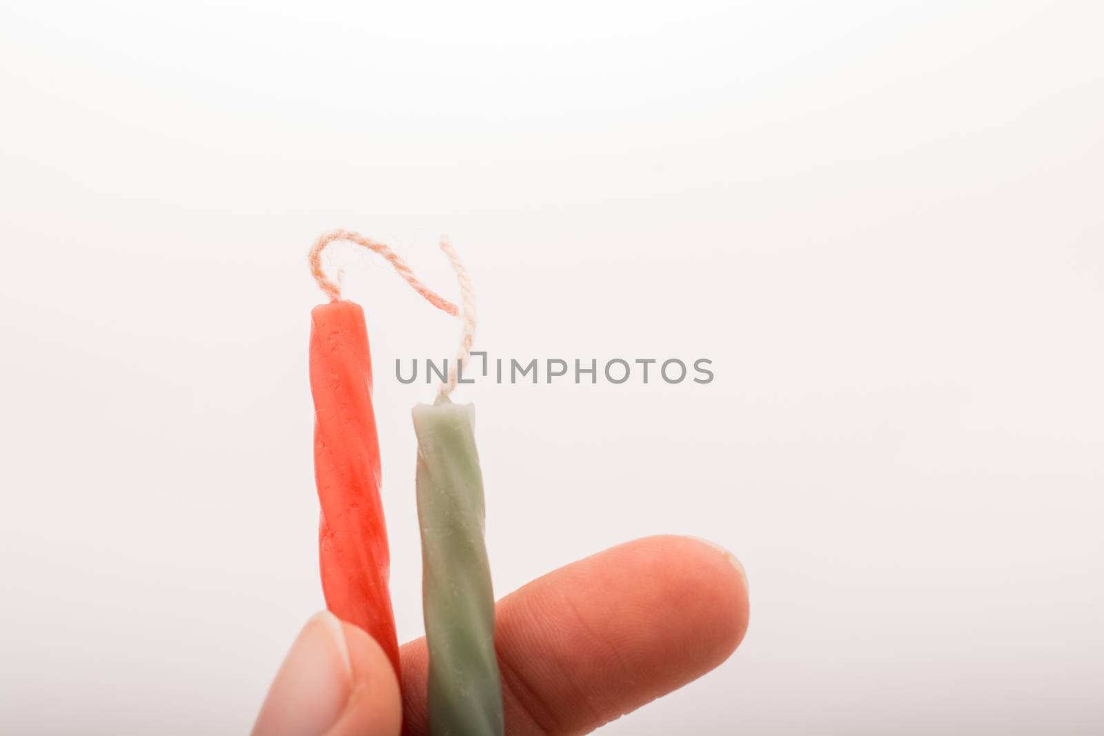 Colorful candle stick in hand on a white background
