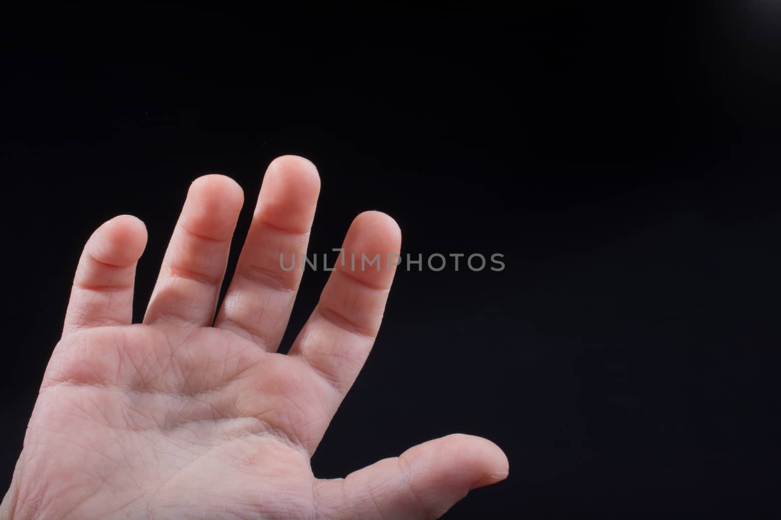 Five fingers of a child hand partly seen in black background