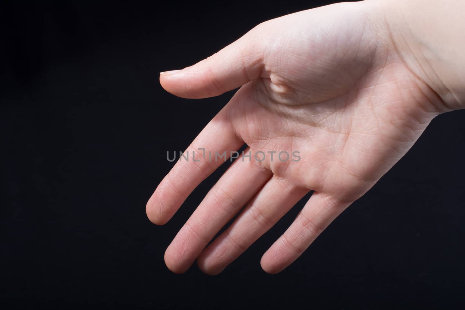 Five fingers of a child hand partly seen in black background