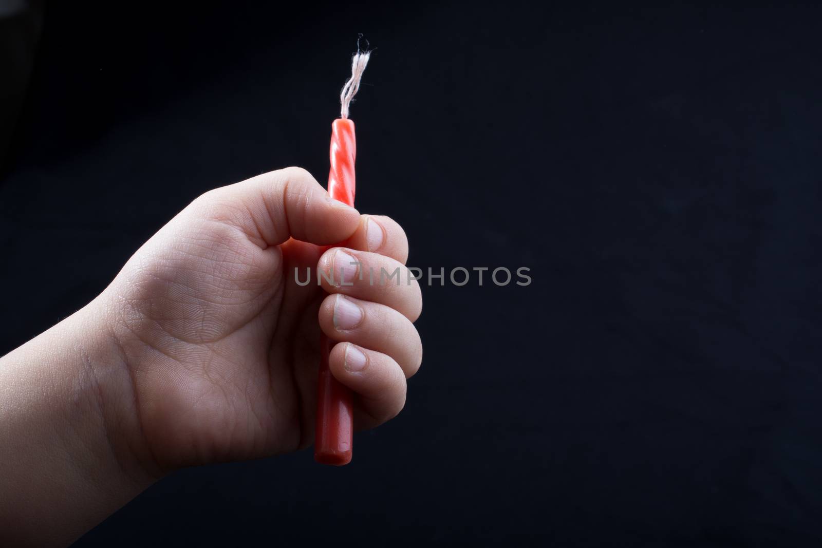 Colorful candle in hand on black background