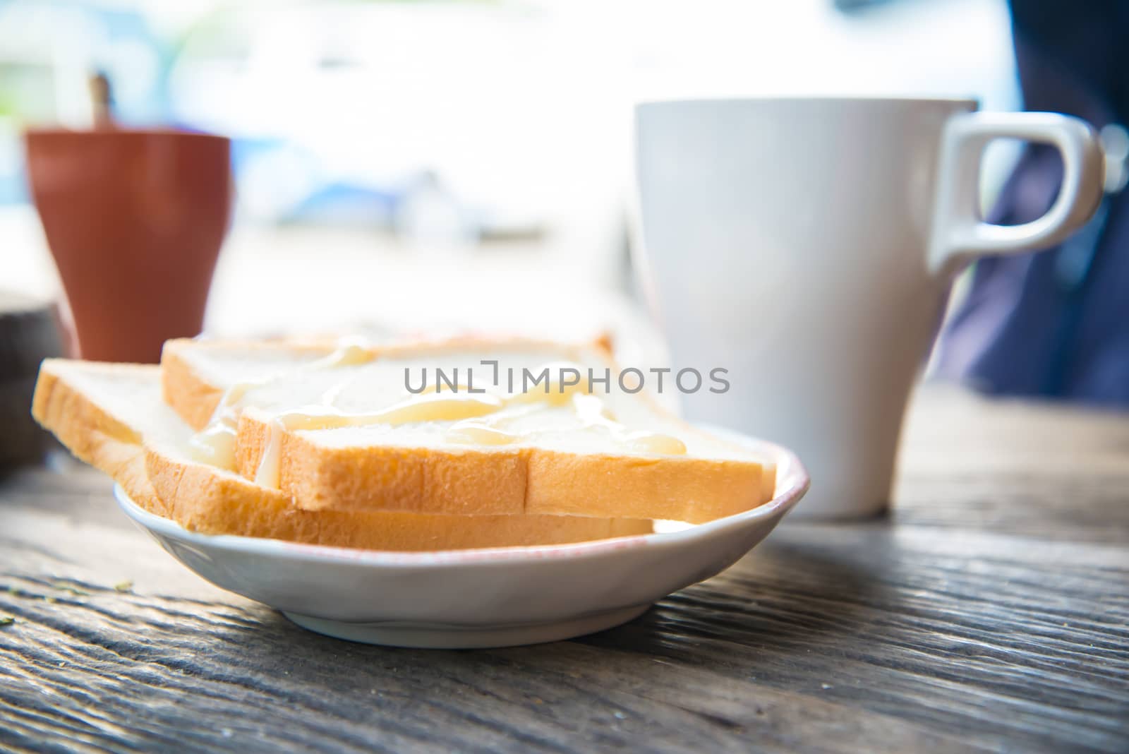 Cup of coffee and a slice of bread on a wooden table.