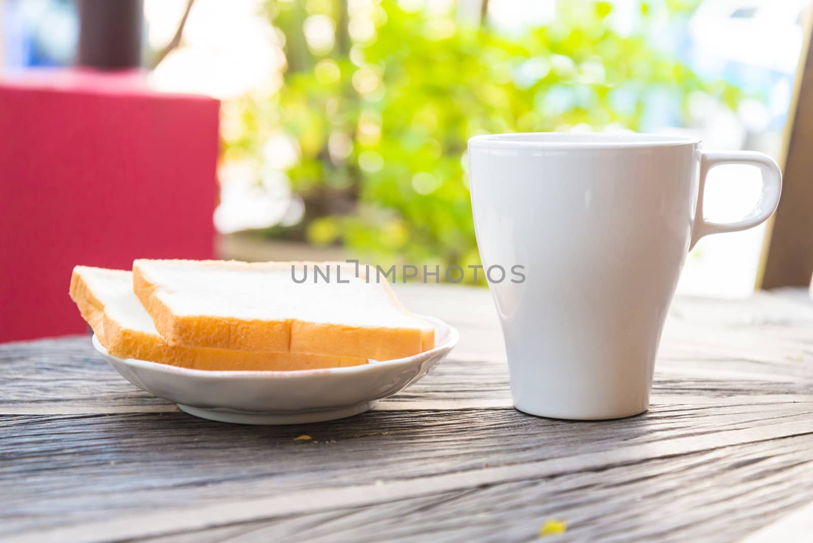 Cup of coffee and a slice of bread on a wooden table.