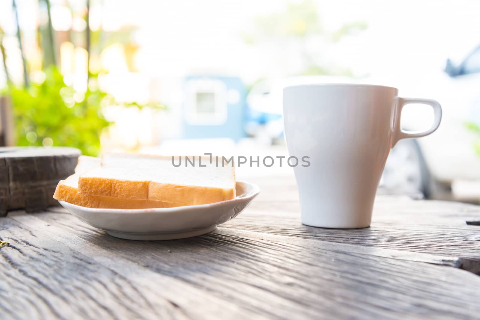 Cup of coffee and a slice of bread on a wooden table.