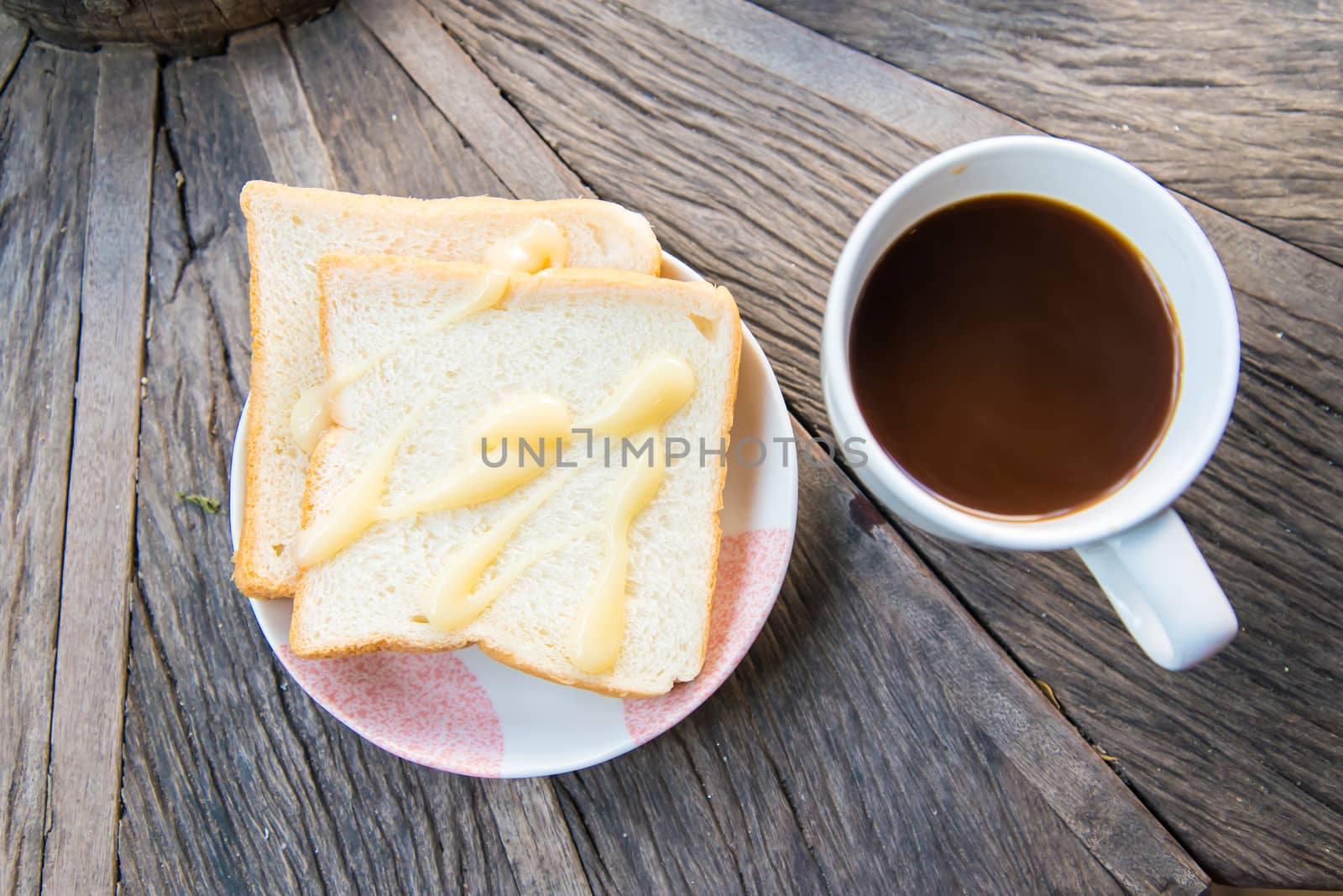 Cup of coffee and a slice of bread on a wooden table.