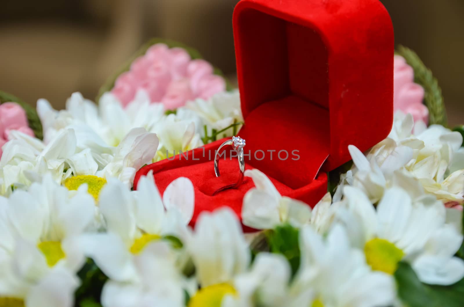 Diamond ring in a red box surrounded by flowers.