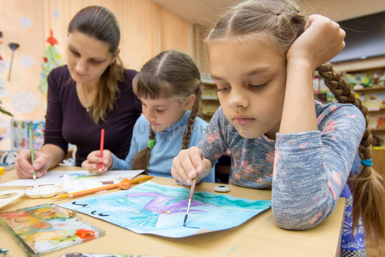 The teacher helps the students in drawing class