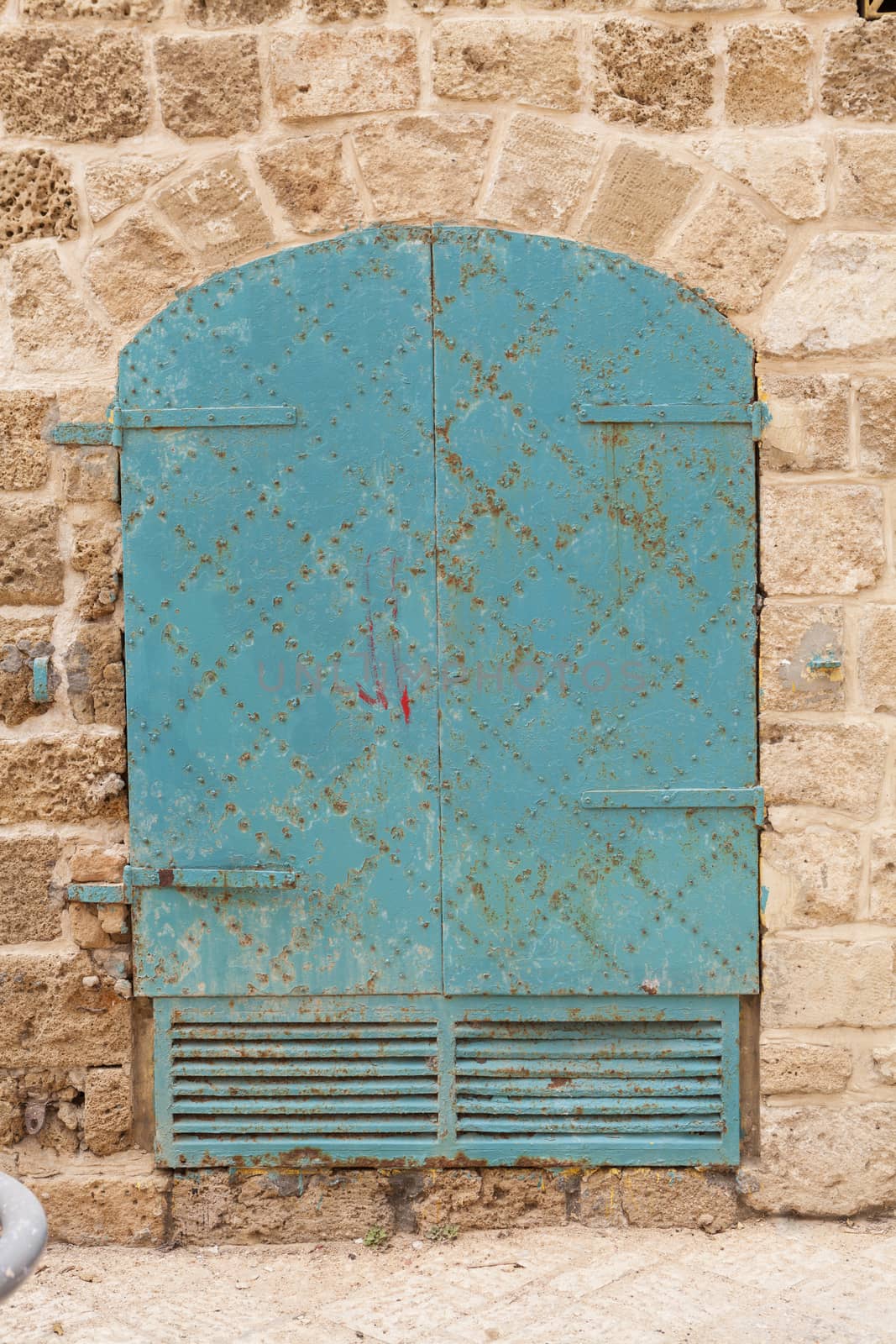 Old rusty iron door on brown stone wall