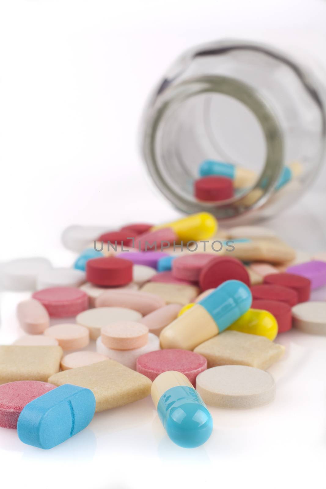 Colorful Pills close-up with spilled from jar isolated on white background