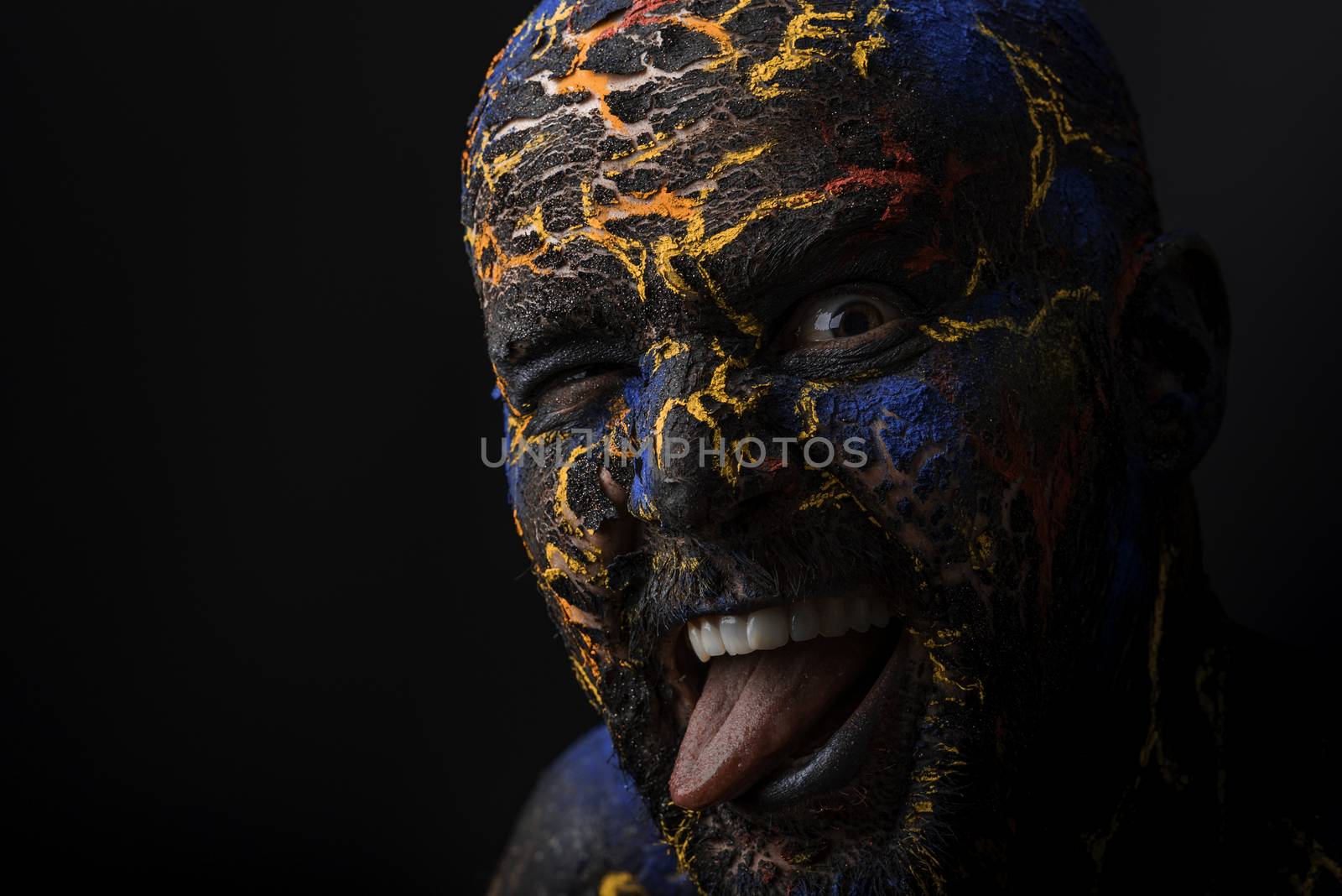 Conceptual Portrait of a brutal man painted in face art style over black background