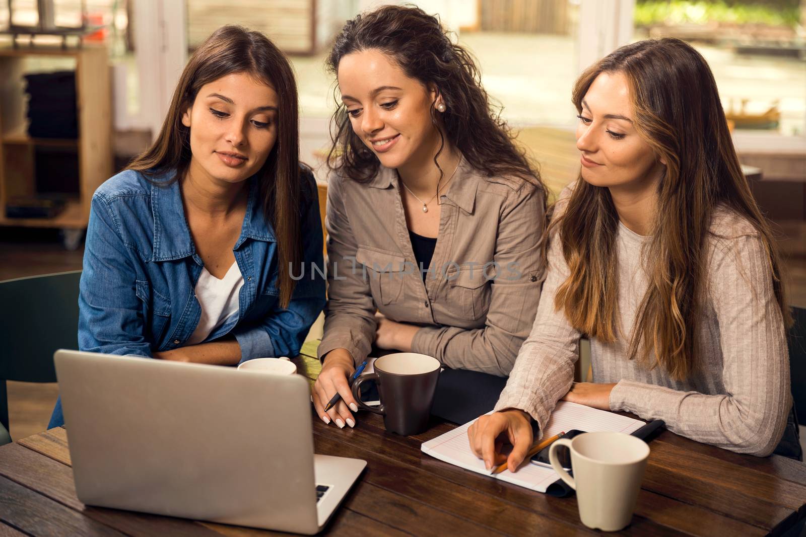 Group of beautiful female friends studying together