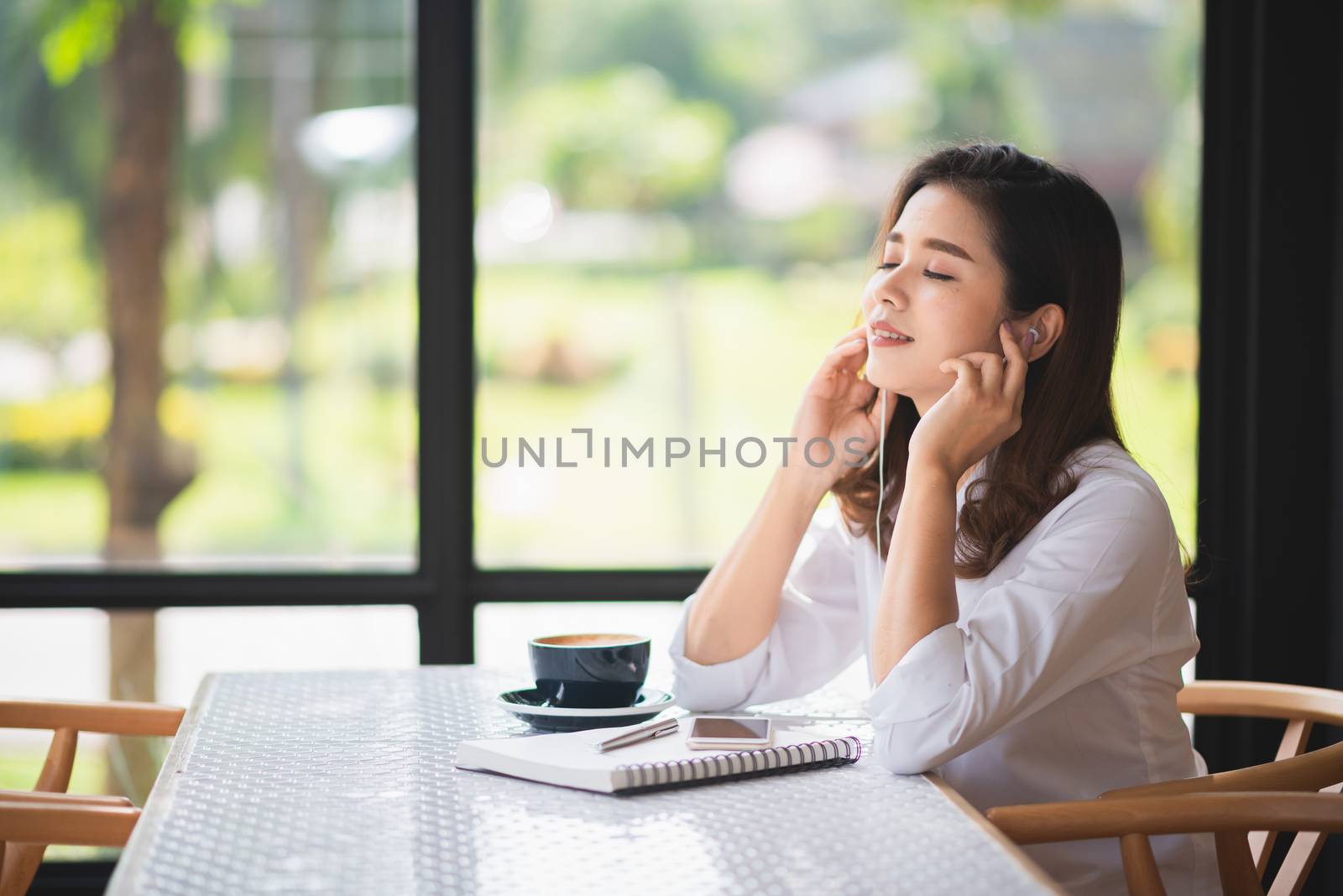 beautiful girl listen music in the cafe and drink some coffee by Wmpix