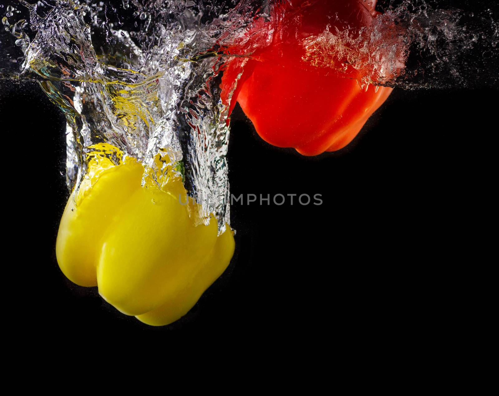 Vegetables tomato and paprika in water splash on black background
