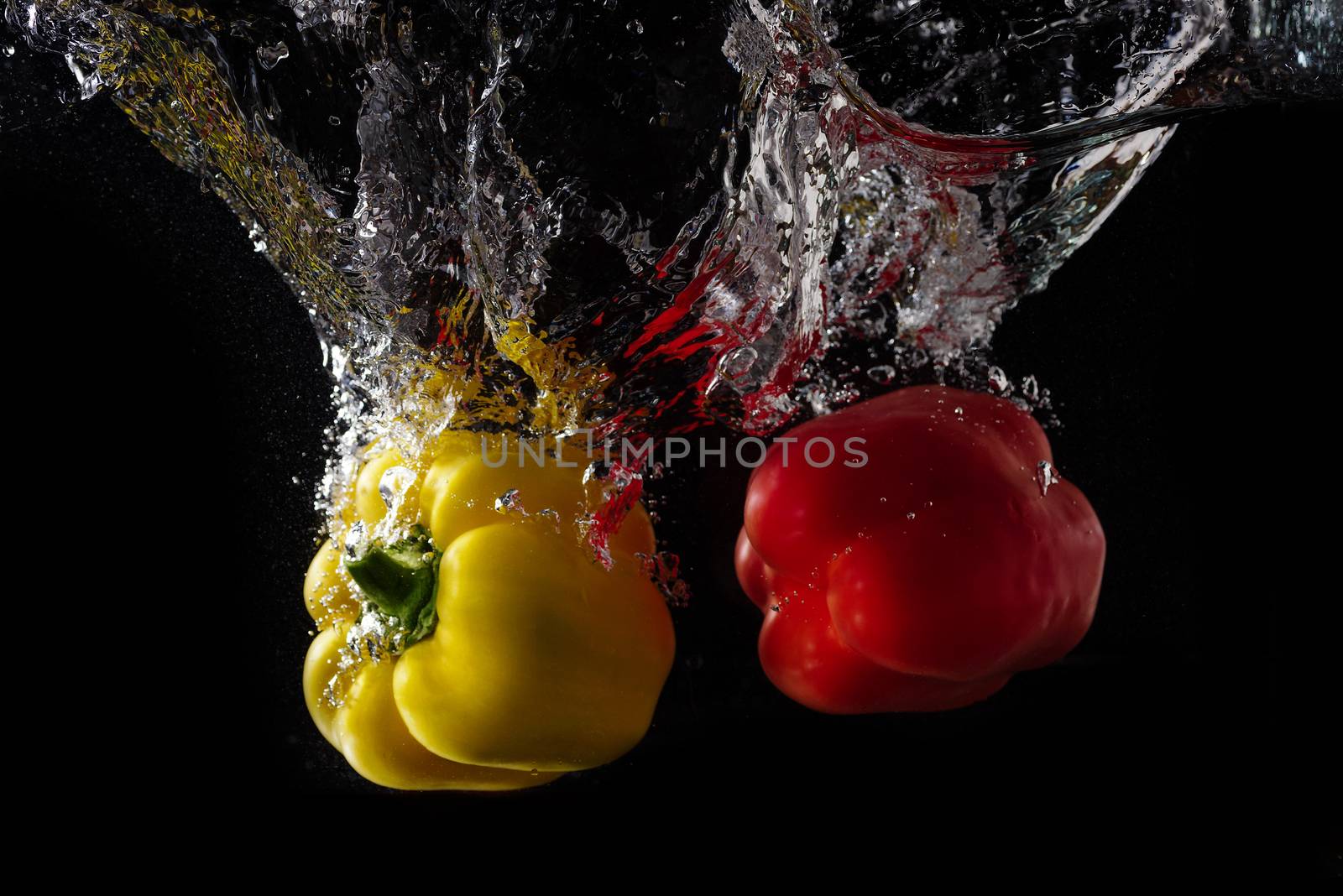 Vegetables tomato and paprika in water splash on black background