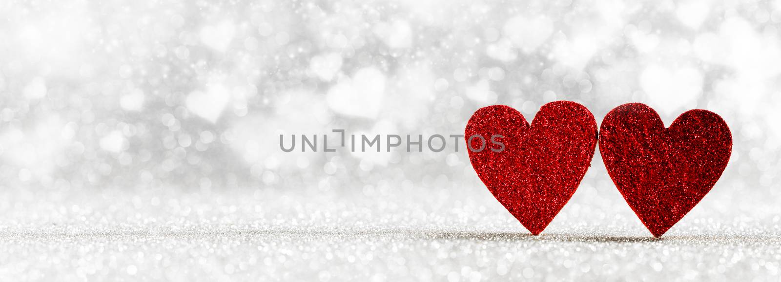 Two red hearts on silver bright glitter lights bokeh background