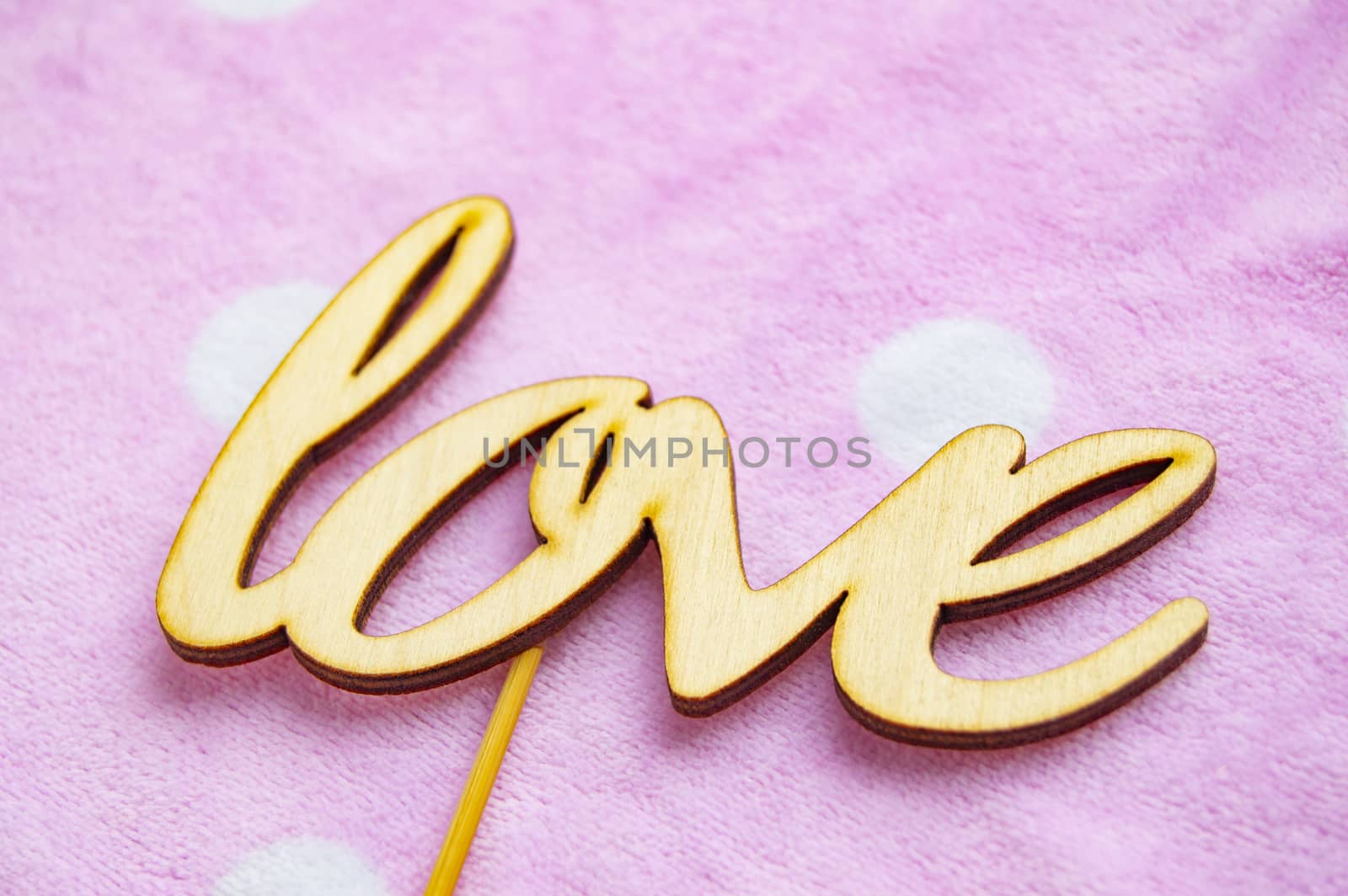 The word love is made of wooden letters on a pink background with white peas. Valentine's day concept, top view by claire_lucia