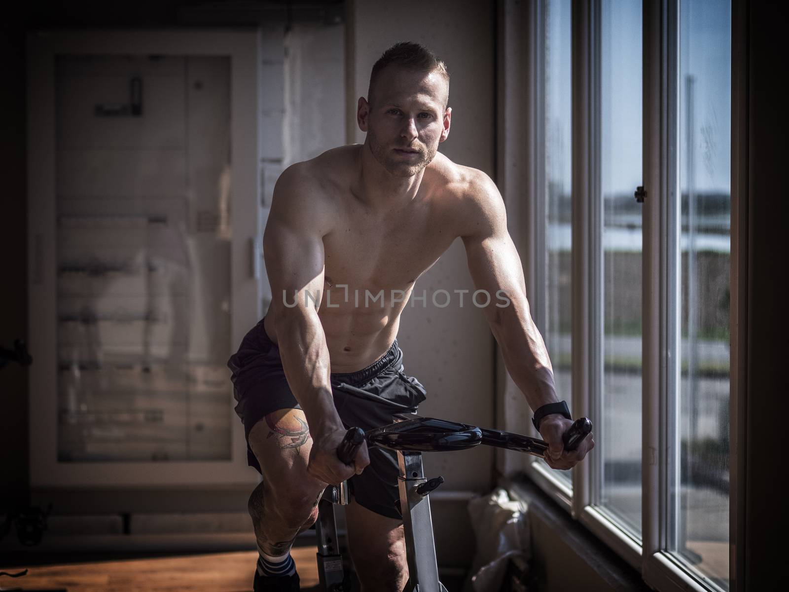 Attractive young man exercising in gym, spinning on stationary bike