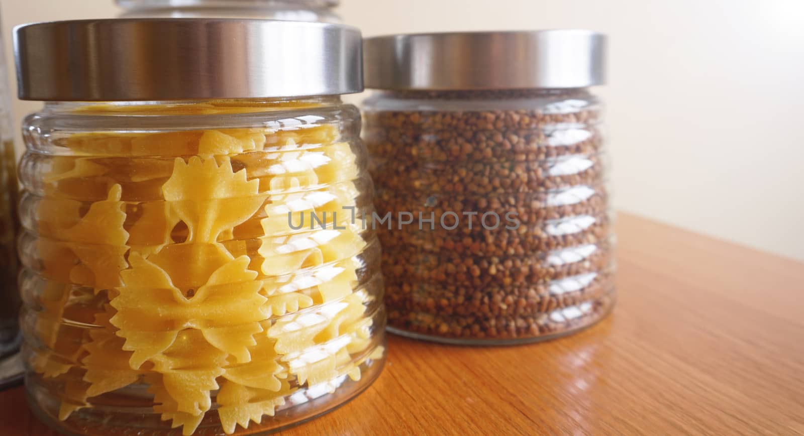 Pasta and bukwheat meals. Healthy cooking in glass jar containers on wooden table. Balanced dieting food.